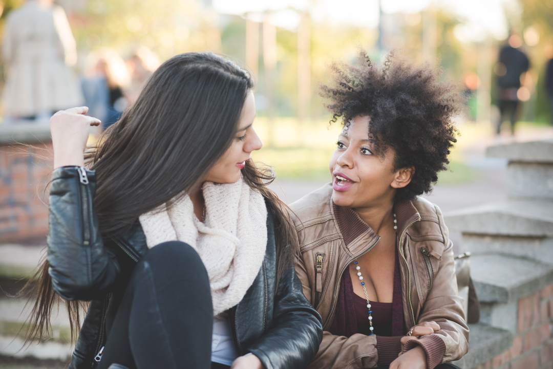 two multiethnic beautiful young woman black and caucasian having fun in town