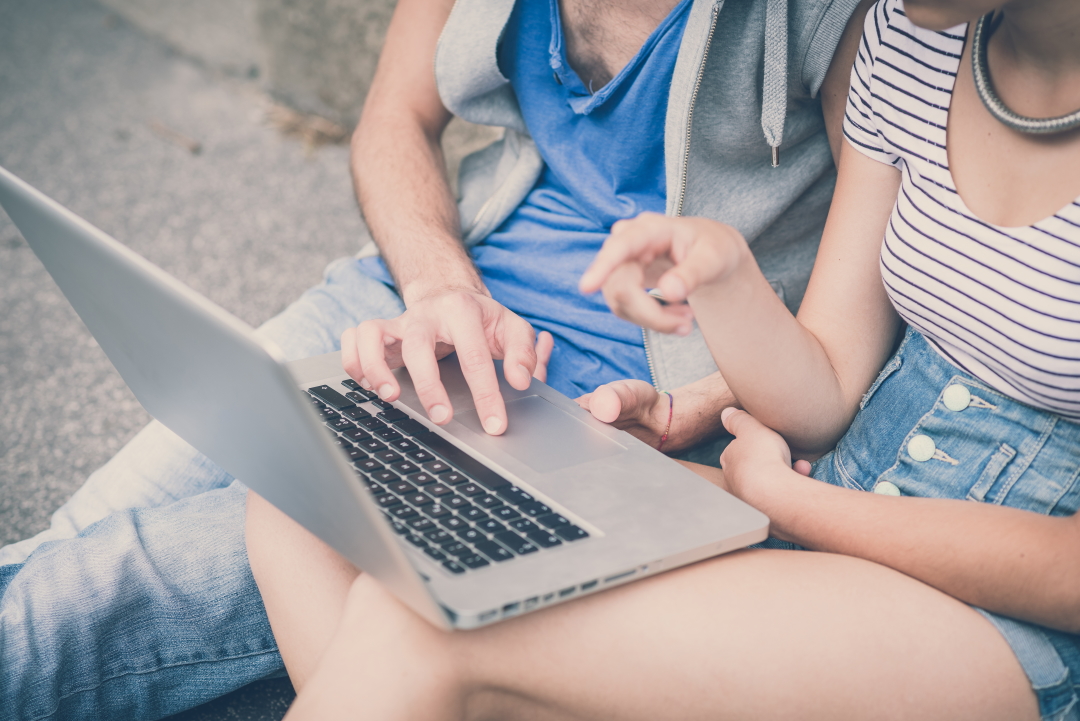 couple of friends young  man and woman using laptop in the city